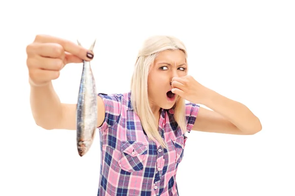 Blond woman holding stinky fish — Stock Photo, Image