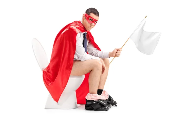 Superhero holding white flag seated on toilet — Stock Photo, Image
