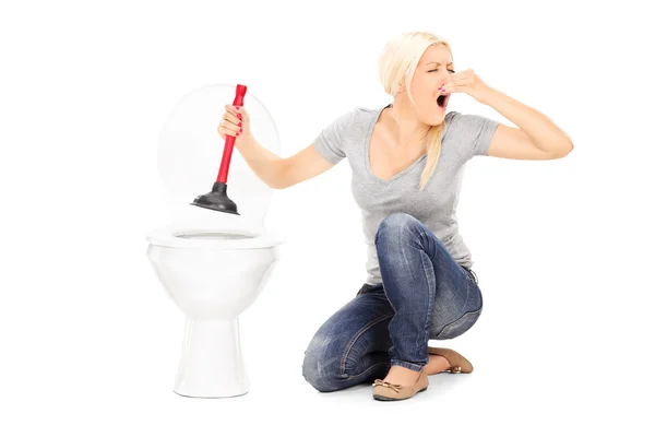 Woman unclogs stinky toilet — Stock Photo, Image
