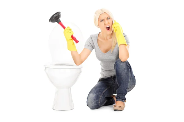 Woman holding plunger talking on phone — Stock Photo, Image