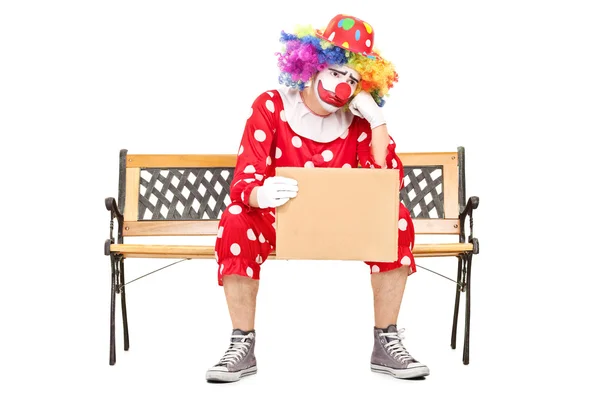 Клоун на скамейке со знаком — стоковое фото