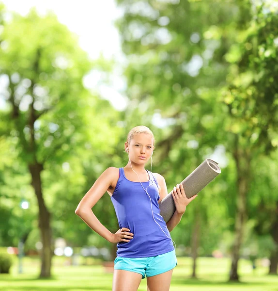 Vrouwelijke atleet bedrijf uitoefening mat — Stockfoto