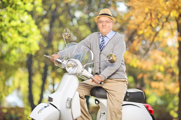 Äldre gentleman på skoter i park — Stockfoto