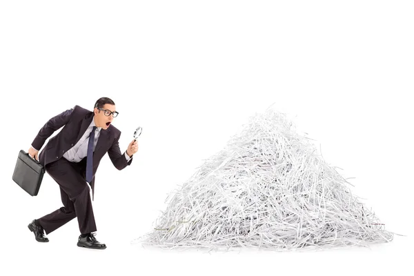 Businessman examining pile of shredded paper — Stock Photo, Image