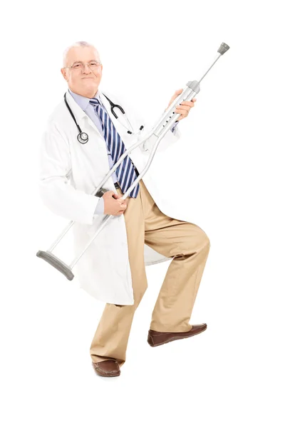 Mature doctor playing guitar on crutch — Stock Photo, Image