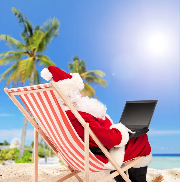 Santa med laptop på stranden — Stockfoto