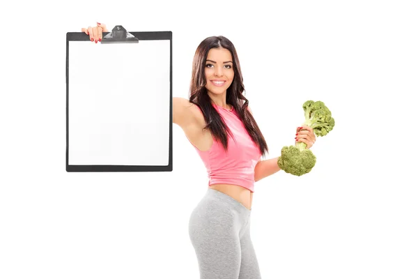Woman holding broccoli dumbbell and clipboard — Stock Photo, Image