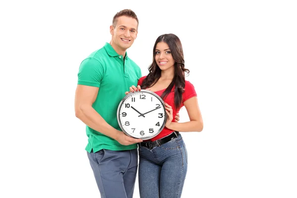 Pareja joven sosteniendo reloj de pared — Foto de Stock