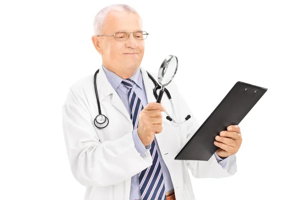 Зрелый врач осматривает документ — стоковое фото