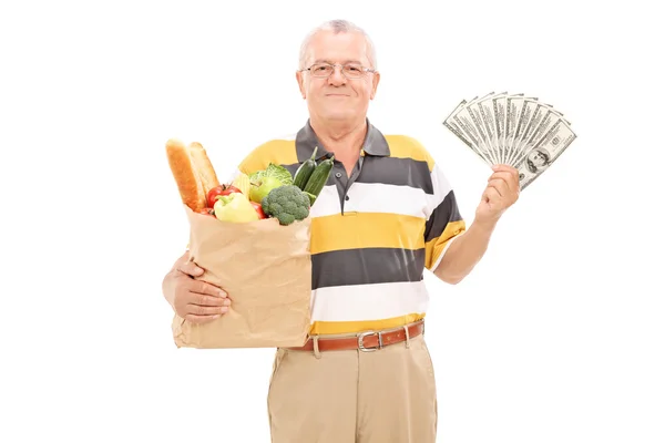 Senior holding kruidenier zak en geld — Stockfoto