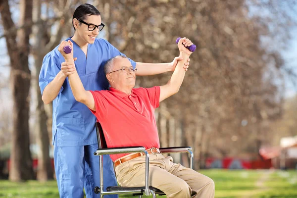 Fisioterapeuta haciendo ejercicio con el paciente en el parque — Foto de Stock