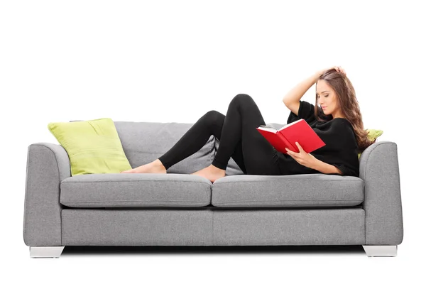 Frau liest Buch auf Sofa — Stockfoto