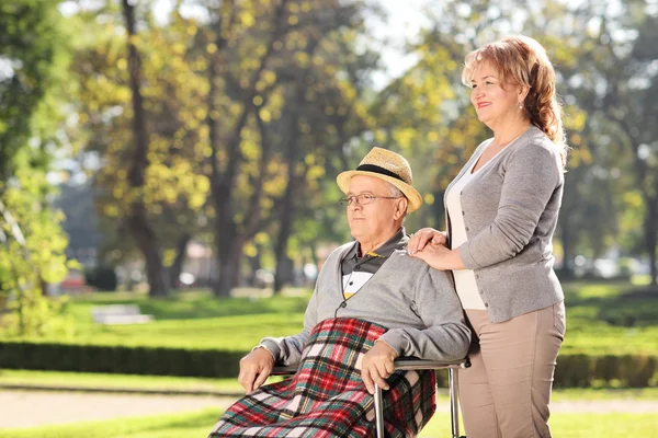 Muž na invalidním vozíku s manželkou v parku — Stock fotografie