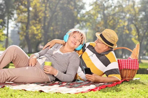 Ouder paar luisteren muziek op picknick — Stockfoto