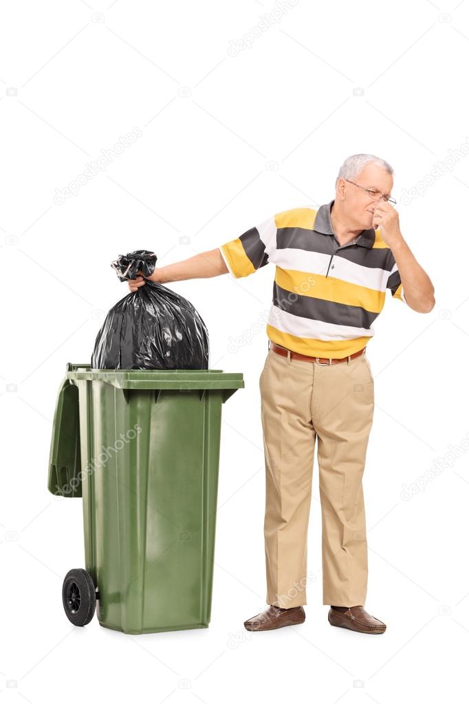 Senior throwing away bag of trash