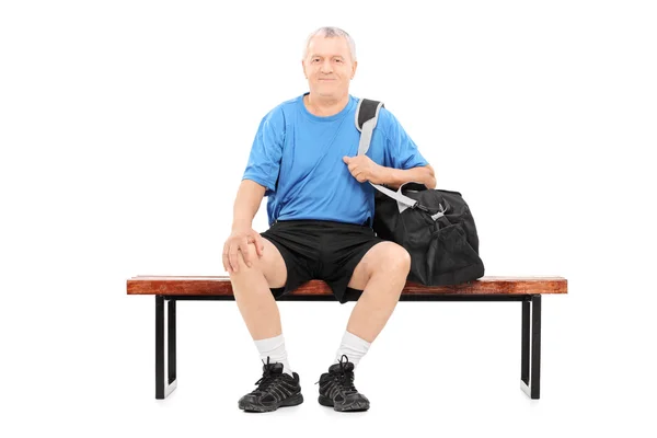 Senior avec sac de sport sur banc — Photo