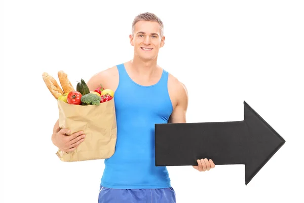 Atleta segurando saco de supermercado e seta — Fotografia de Stock