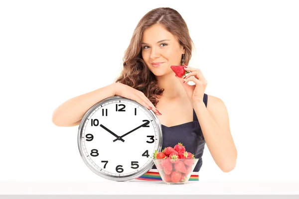 Woman holding strawberry and clock — Stock Photo, Image