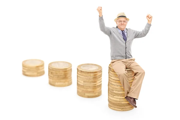 Senior seated on coin pile — Stock Photo, Image