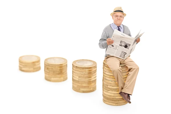 Senior seated on coin pile — Stock Photo, Image