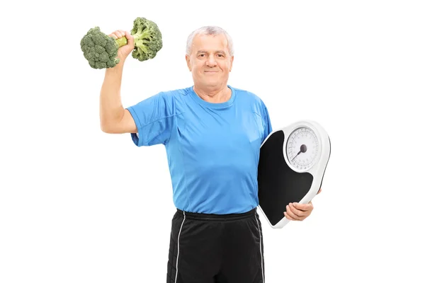 Senior lifting a broccoli dumbbell — Stock Photo, Image