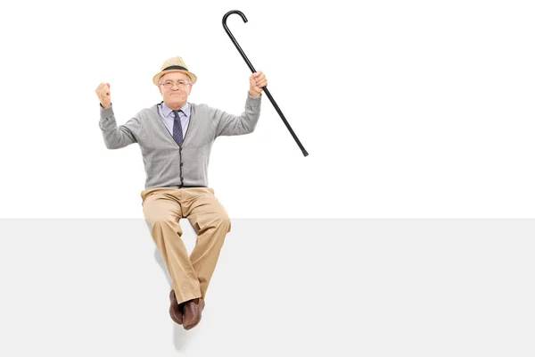 Senior holding cane seated on panel — Stock Photo, Image