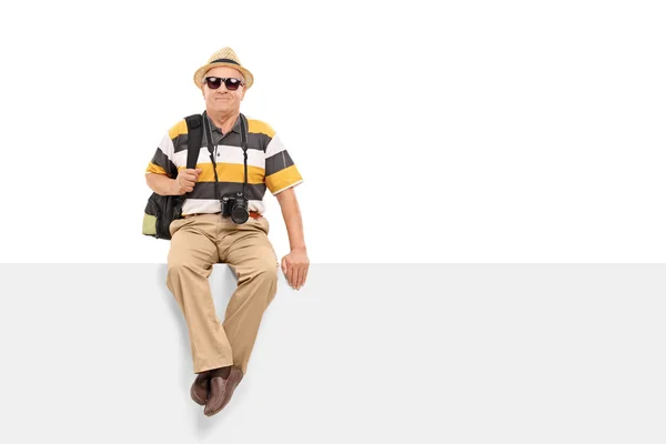 Reifer Tourist sitzt auf leerer Plakatwand — Stockfoto