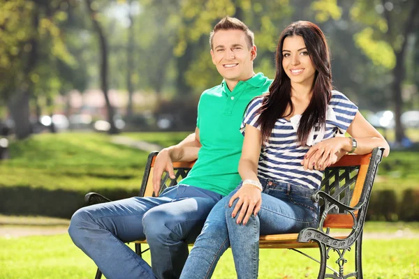 Pari istuu penkillä puistossa — kuvapankkivalokuva