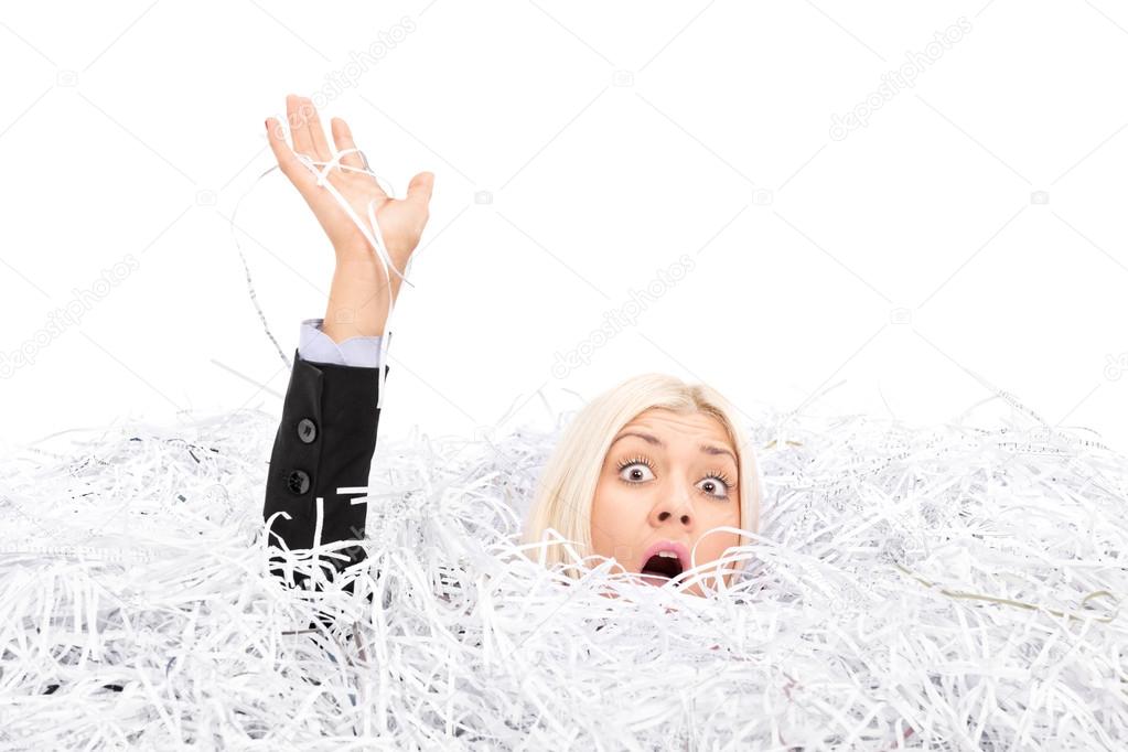 Businesswoman drowning in shredded paper