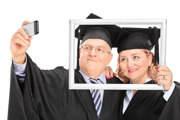 Mature couple taking selfie behind picture frame — Stock Photo, Image