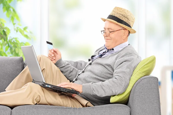 Sénior com laptop e cartão de crédito — Fotografia de Stock