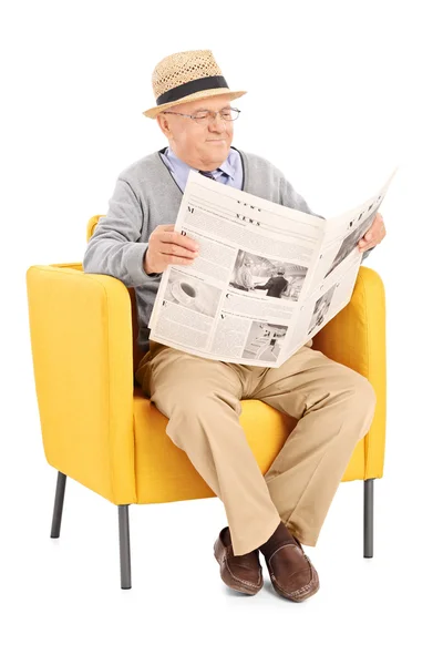 Senior lezing krant in leunstoel — Stockfoto