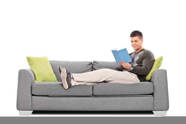 Young guy reading book on sofa — Stock Photo, Image