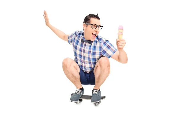 Joven macho sonriente en una tabla de skate con helado — Foto de Stock