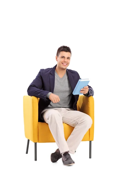 Hombre sosteniendo libro en sillón — Foto de Stock