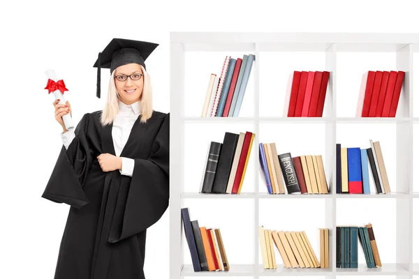 Absolventin lehnt an Bücherregal — Stockfoto