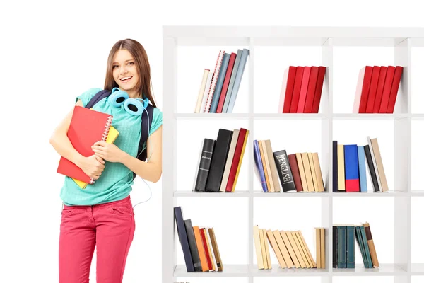 Female student leaning against bookshelf — Stock Photo, Image