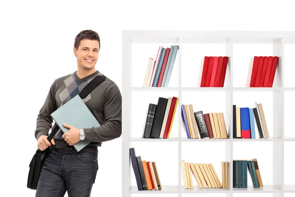 Студент-мужчина, опирающийся на книжную полку — стоковое фото