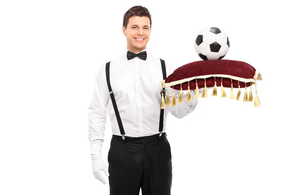 Butler holding pillow with football — Stock Photo, Image