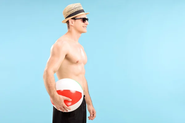 Hombre sin camisa sosteniendo pelota de playa —  Fotos de Stock