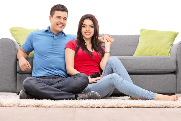 Young couple seated on carpet — Stock Photo, Image
