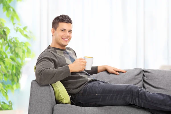 Человек пьет кофе на диване — стоковое фото