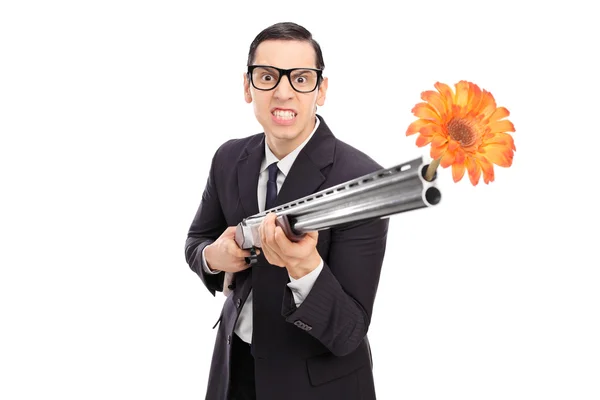 Businessman shooting flowers from rifle — Stock Photo, Image