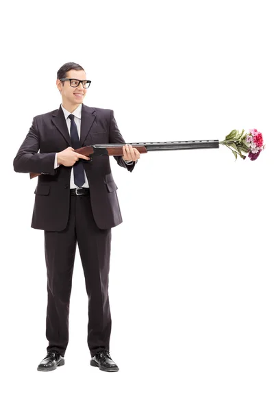 Businessman holding rifle loaded with flowers — Stock Photo, Image