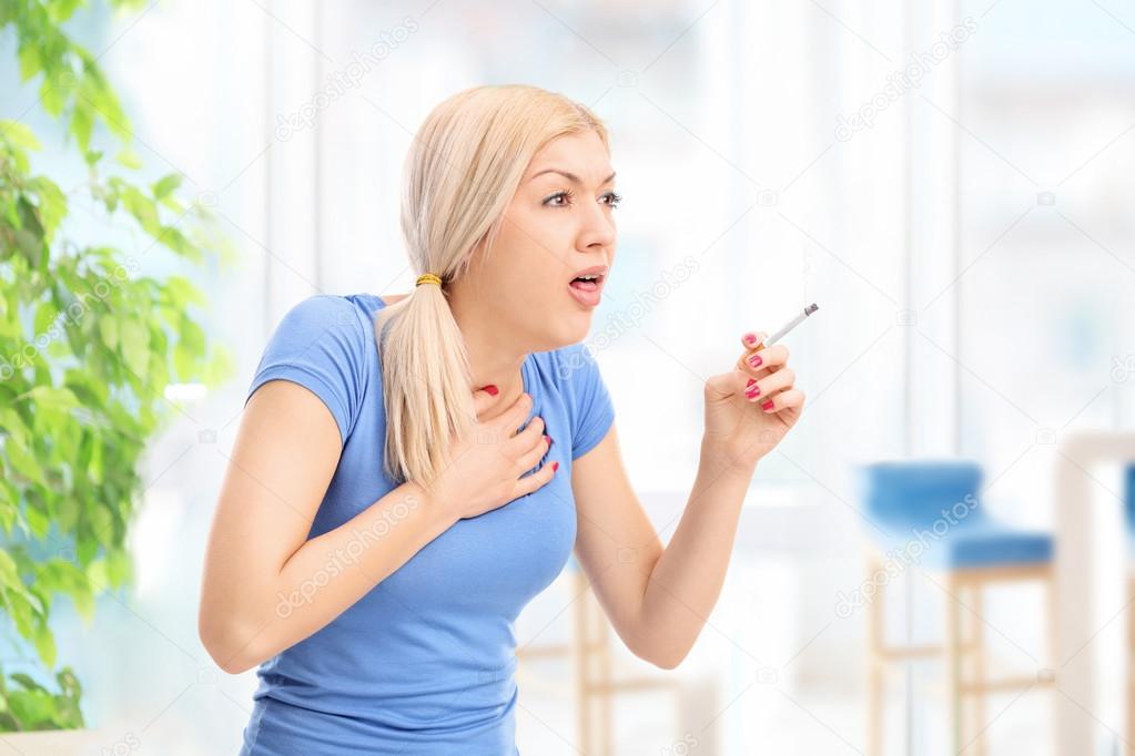 Young woman coughing from cigarette