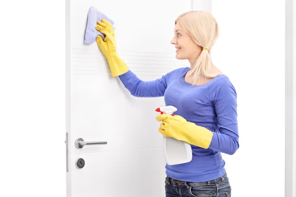 Mladá žena čištění dveře — Stock fotografie