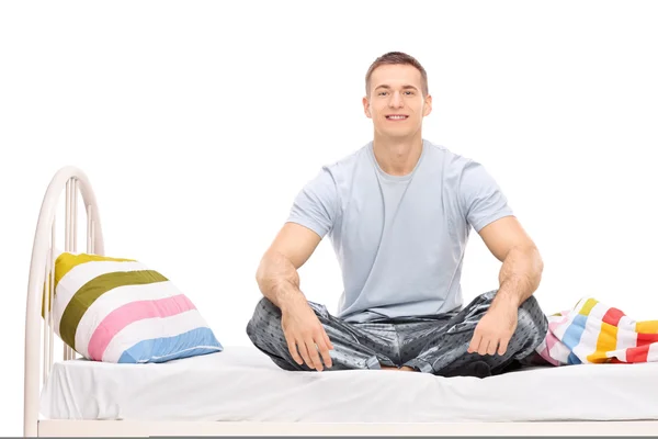 Человек в пижаме сидит на кровати — стоковое фото