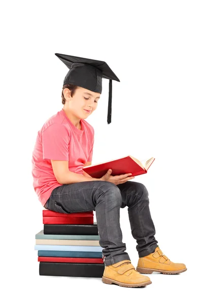 Kid with mortarboard reading book — Stock Photo, Image