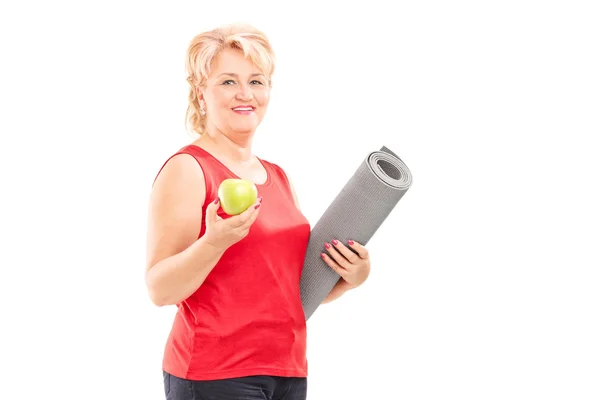 Mujer sosteniendo manzana y estera — Foto de Stock