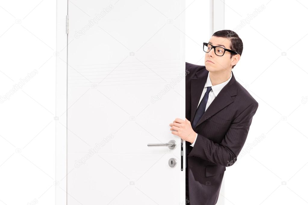 Businessman peeking through opened door